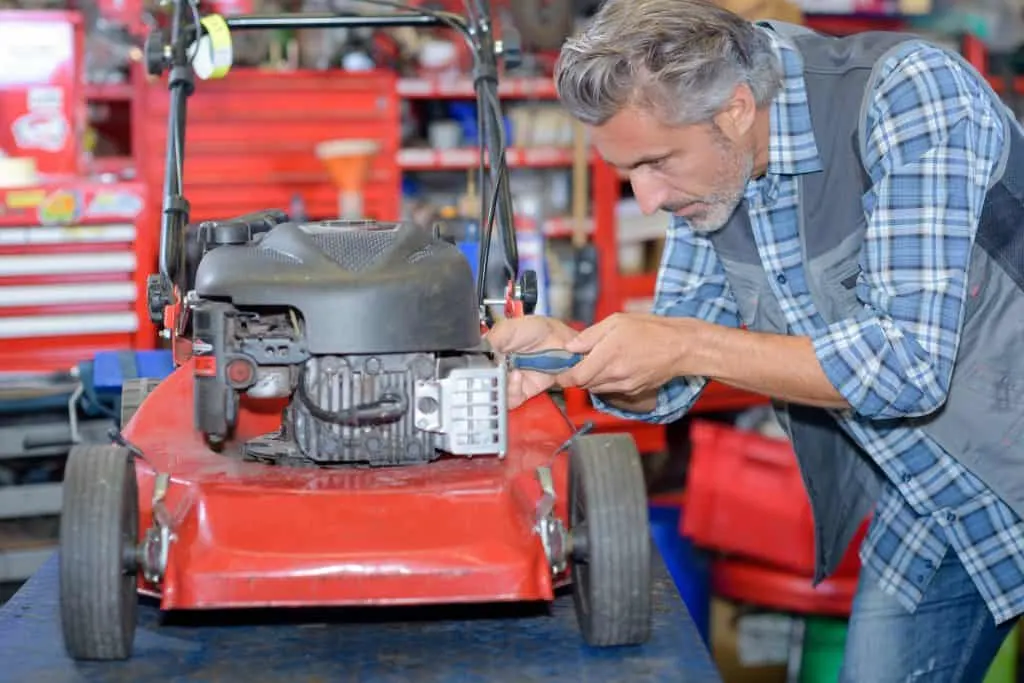 Small engine mechanic working on lawn mower due to the engine requiring starter fluid to start.